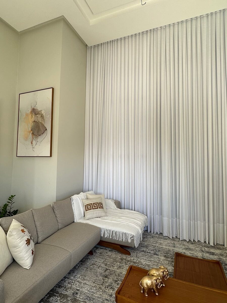 Sala de estar com cortina de voil branca do chão ao teto, instalada pela Paris Decoração de Interiores