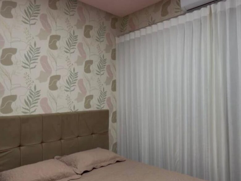 Quarto com papel de parede de folhagem e cortina clara na janela
