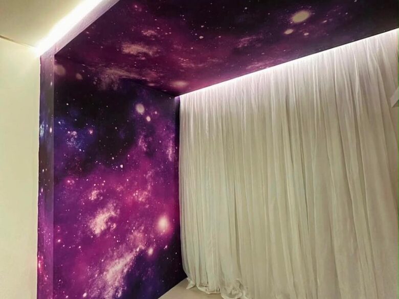 Outro ângulo do quarto com painel de galáxia e cortina clara
